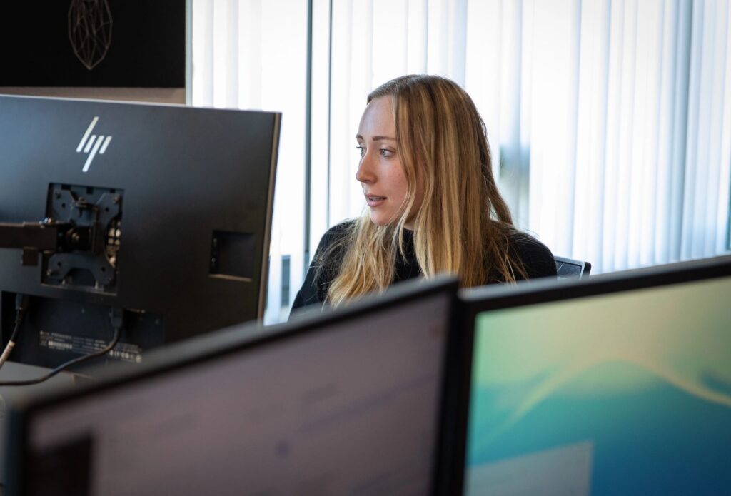 Persoon werkt achter computer en bekijkt gegevens op scherm