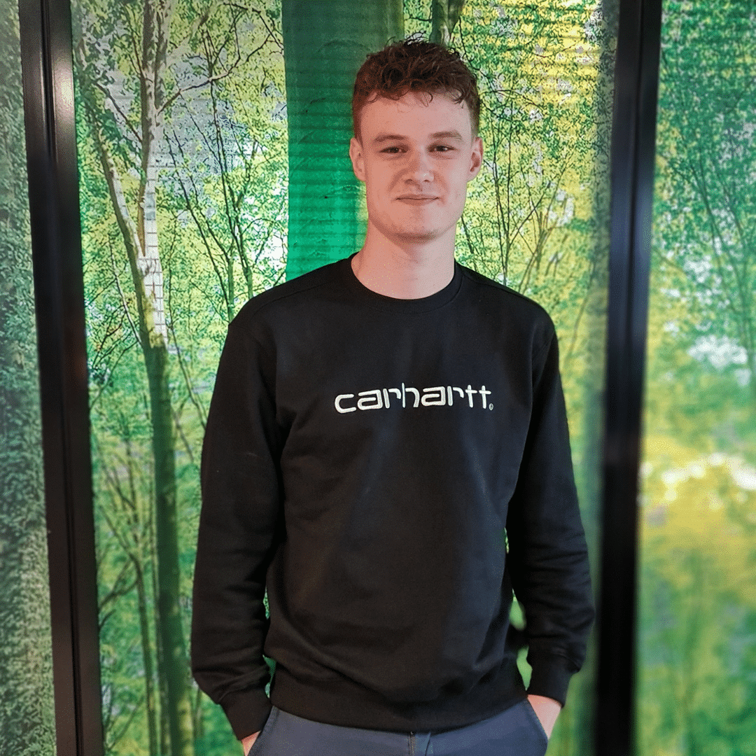 Wiebe junior online marketeer bij Positie1 staand voor groene achtergrond met bomenprint