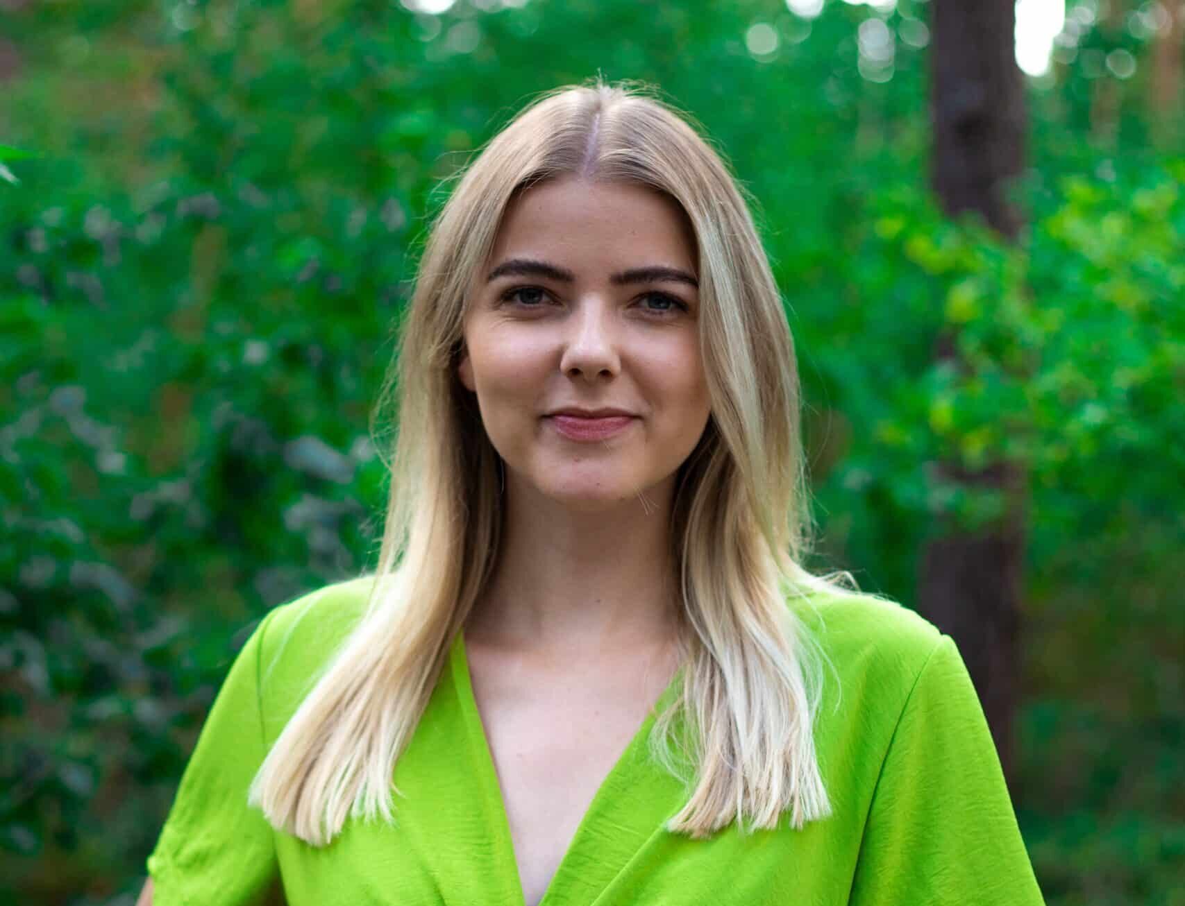 Leonie grafisch vormgever bij Rebelation en Positie1 staand in groene omgeving