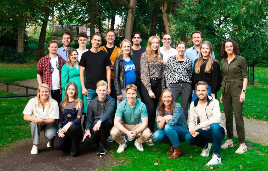 Team van Positie1 en Rebelation samen op groepsfoto buiten in groene omgeving