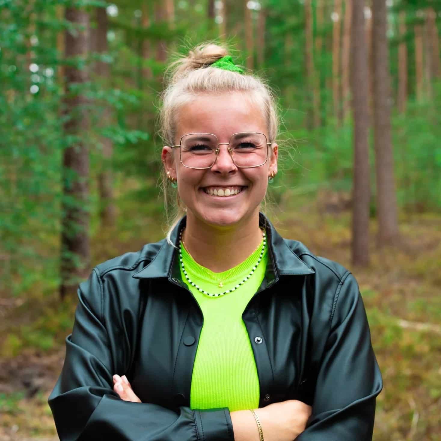 Anne grafisch vormgever bij Rebelation en Positie1 lachend portret in bosrijke omgeving