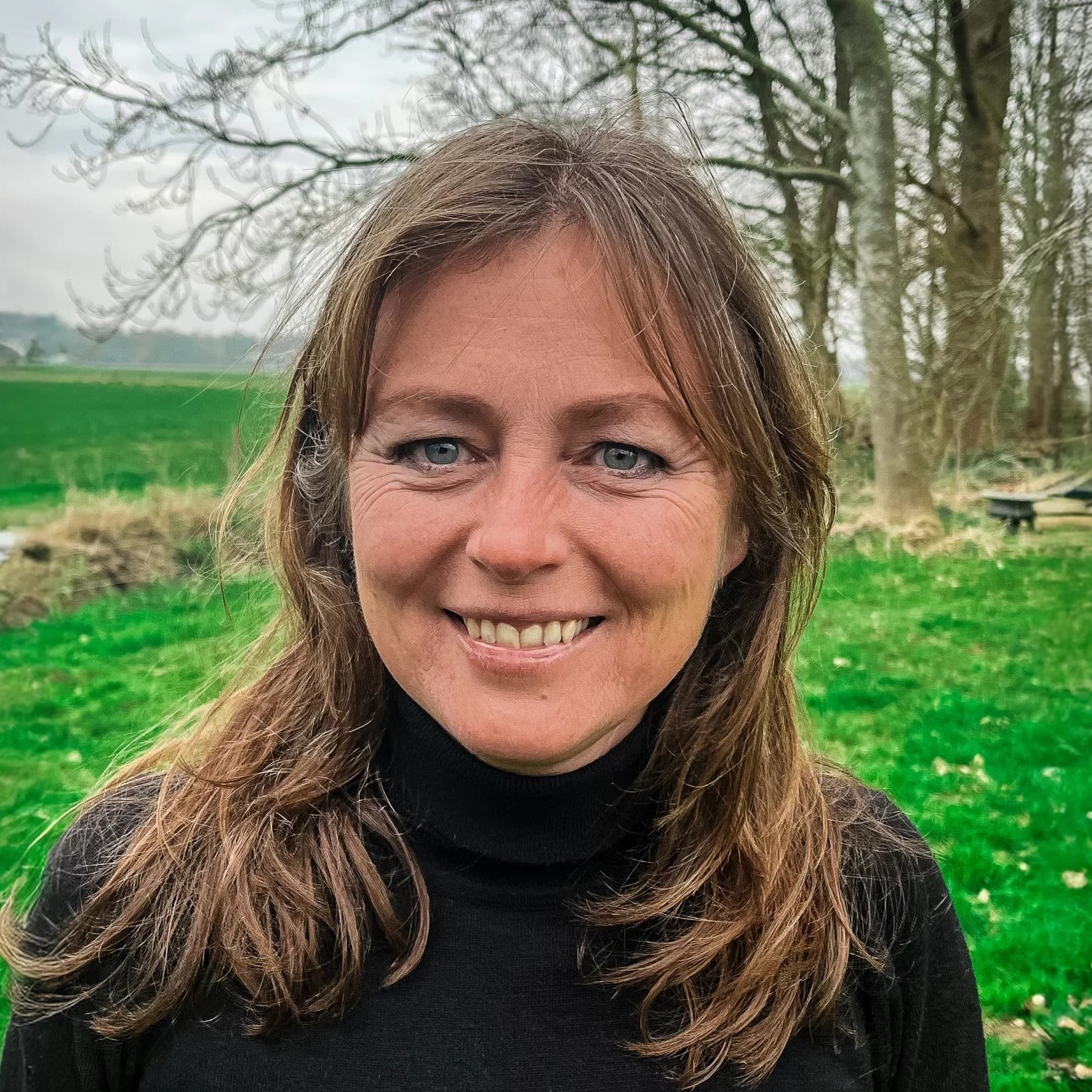 Janine creatief strateeg bij Rebelation en Positie1 lachend portret in groene buitenomgeving