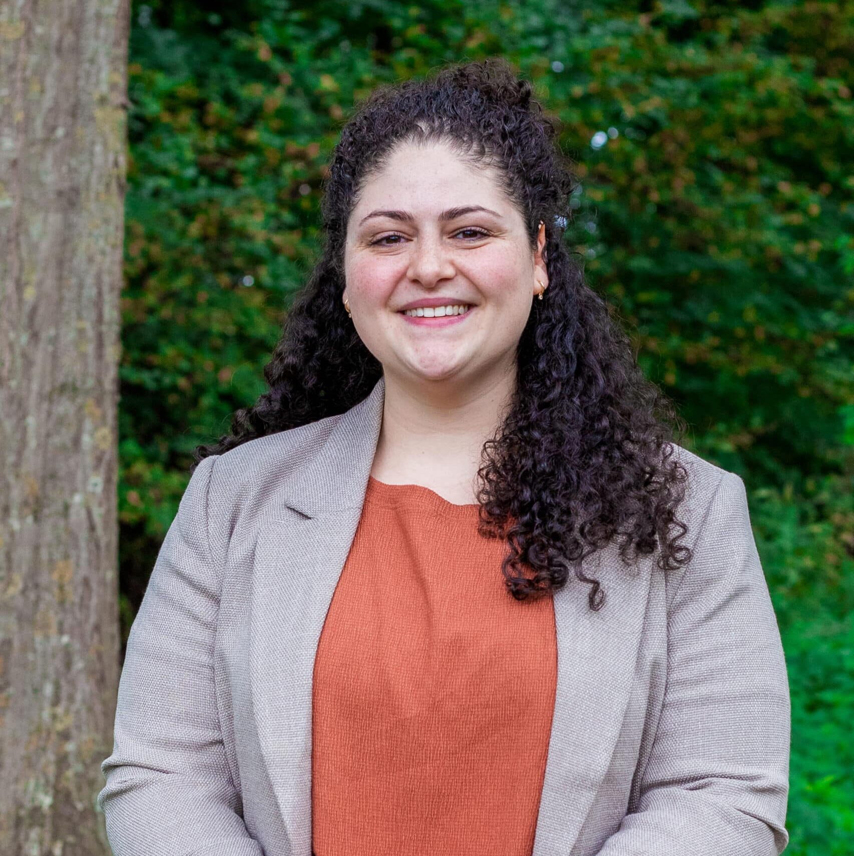 Lara, managementassistent bij Positie1, portretfoto buiten in een groene omgeving