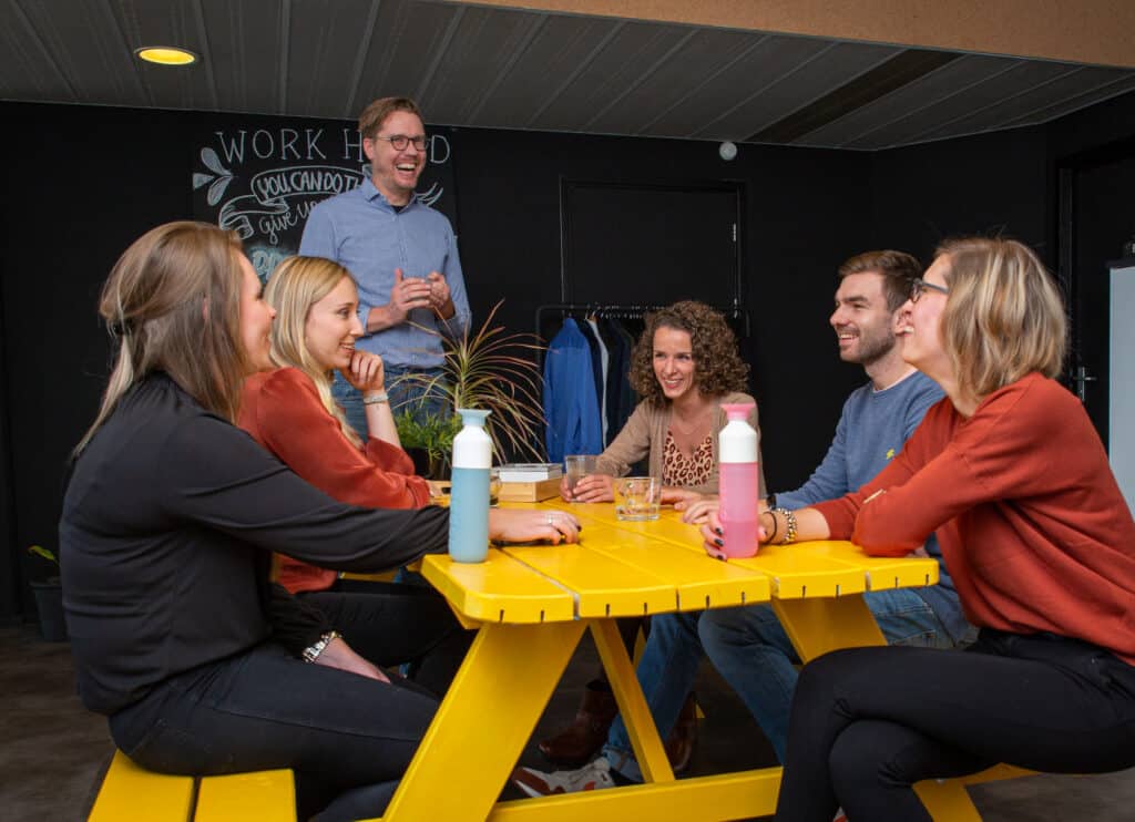 Team zit samen aan tafel en overlegt in informele setting
