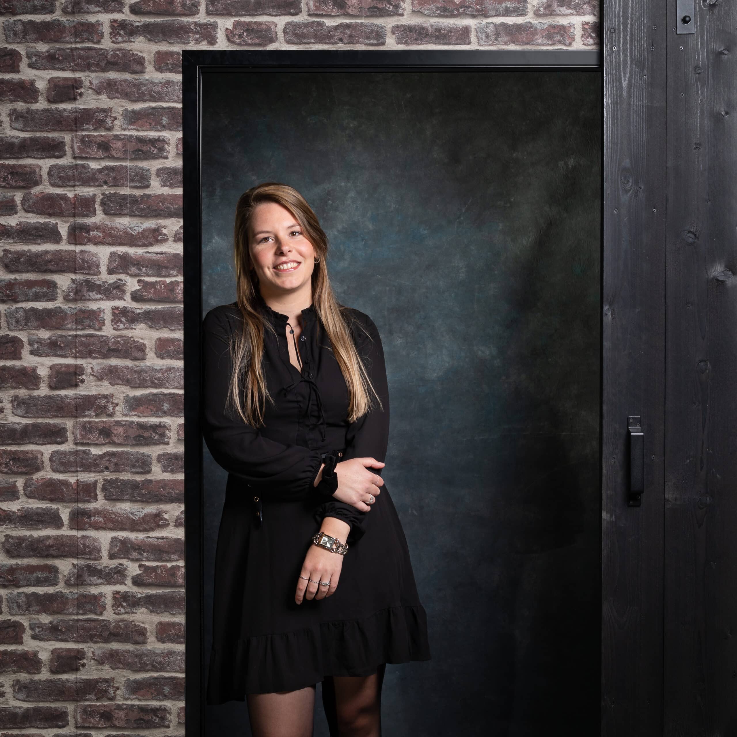 Ilona content- en social mediaspecialist bij Positie1 staand bij industriële deur met bakstenen muur