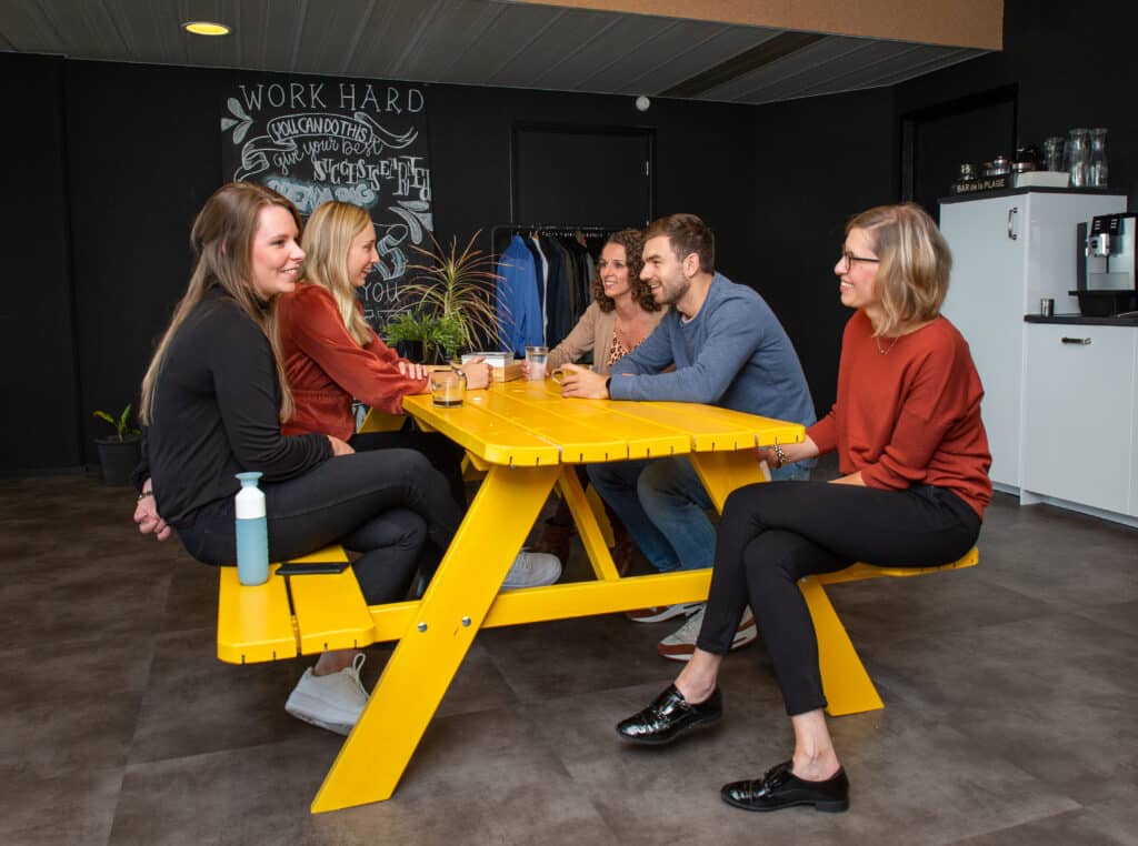 Team zit samen aan tafel en overlegt in informele setting
